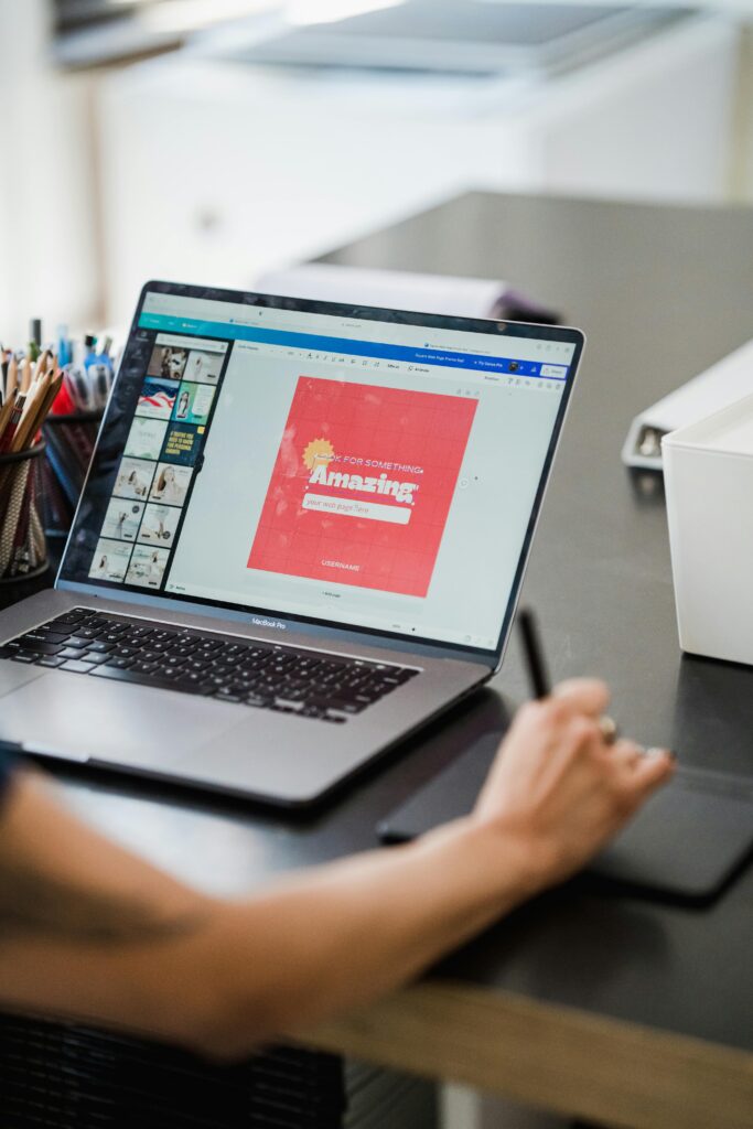Person using a laptop and graphic tablet for digital design work in a home office.